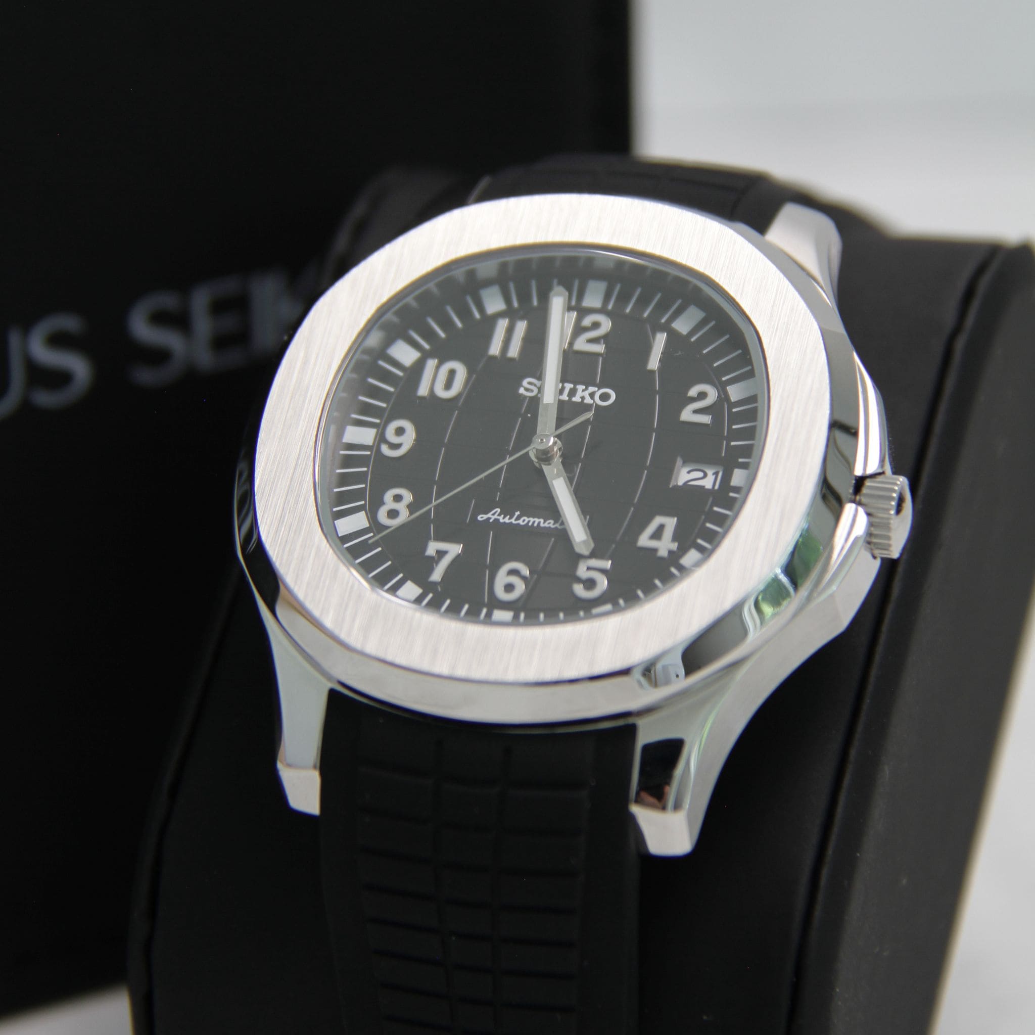 Montre Seiko Mod aquanaut noir sur coussin noir avec écrin en arrière plan.