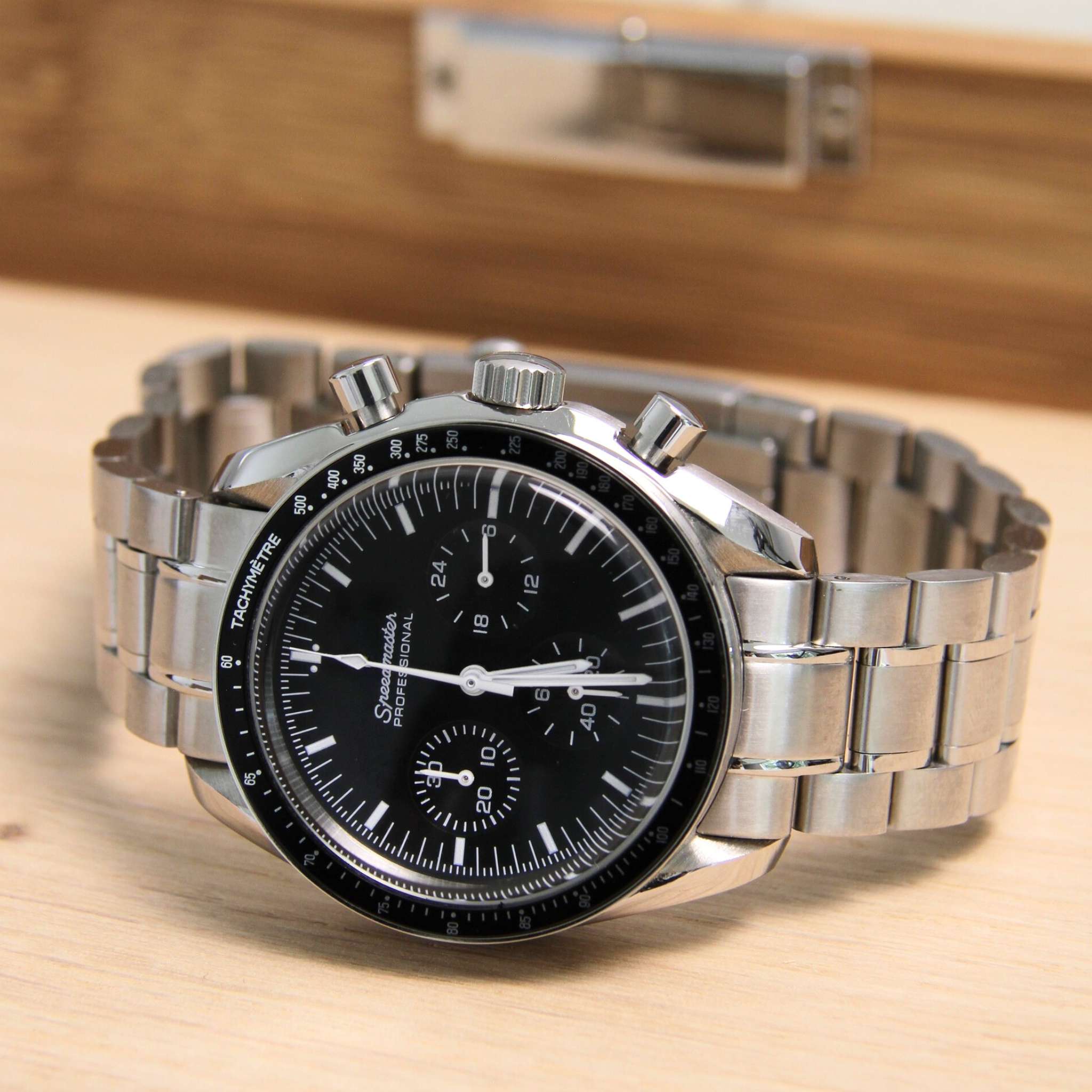 “Montre SEIKMOD Speedmaster Noir VK63 vue complète à plat, cadran noir tricompax et lunette tachymétrique argentée”